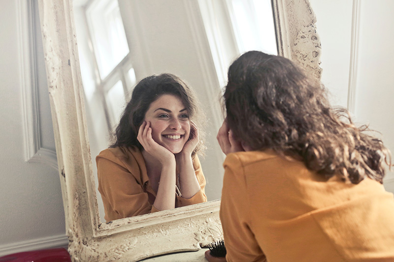a woman looking at the mirror smiling