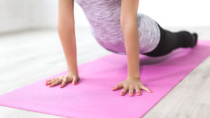 a woman doing a yoga pose on a pink yoga mat