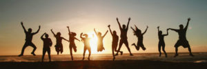 people jumping on the beach at sunset