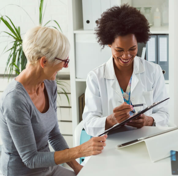 female african american doctor reviewing a chart with a mature female patient