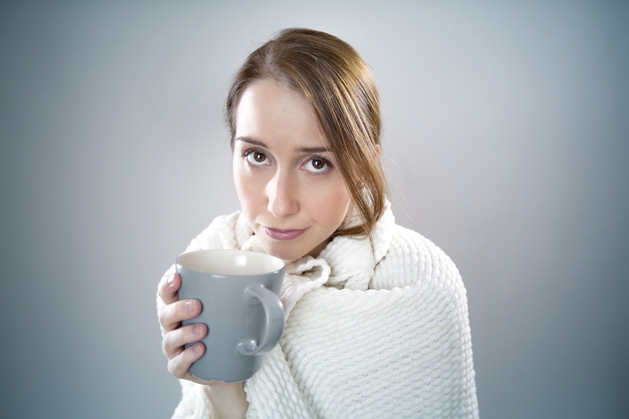 Sick Woman Wrapped in a Blanket Holding a Mug