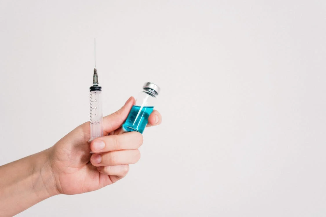 Person holding a syringe and vial