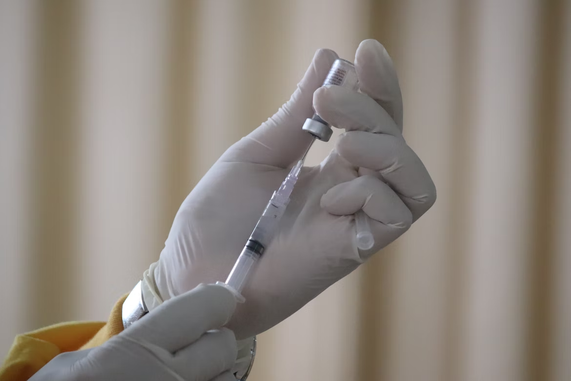 Hand holding a syringe and vial