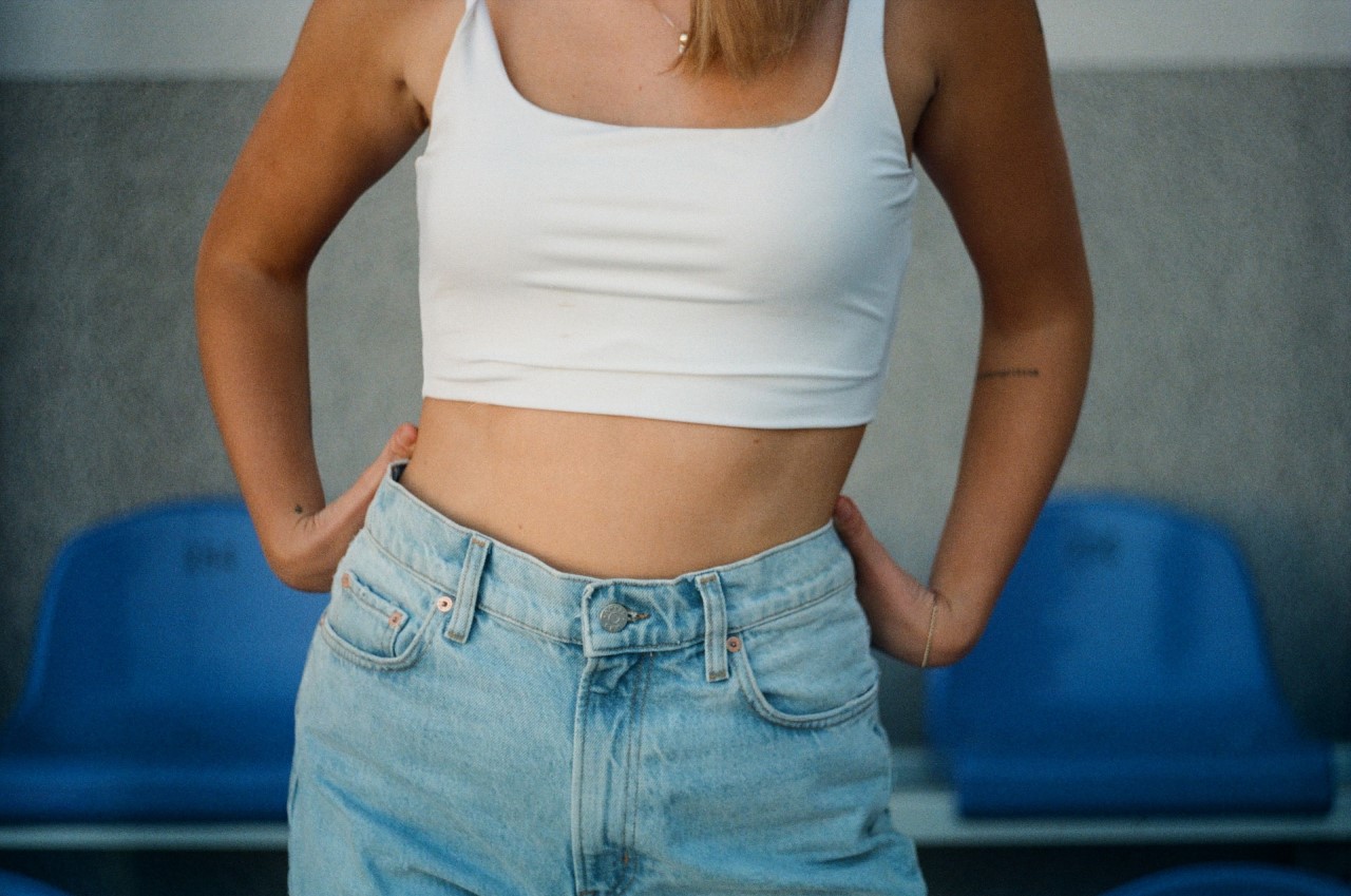 Person in jean shorts and a crop top with an exposed stomach