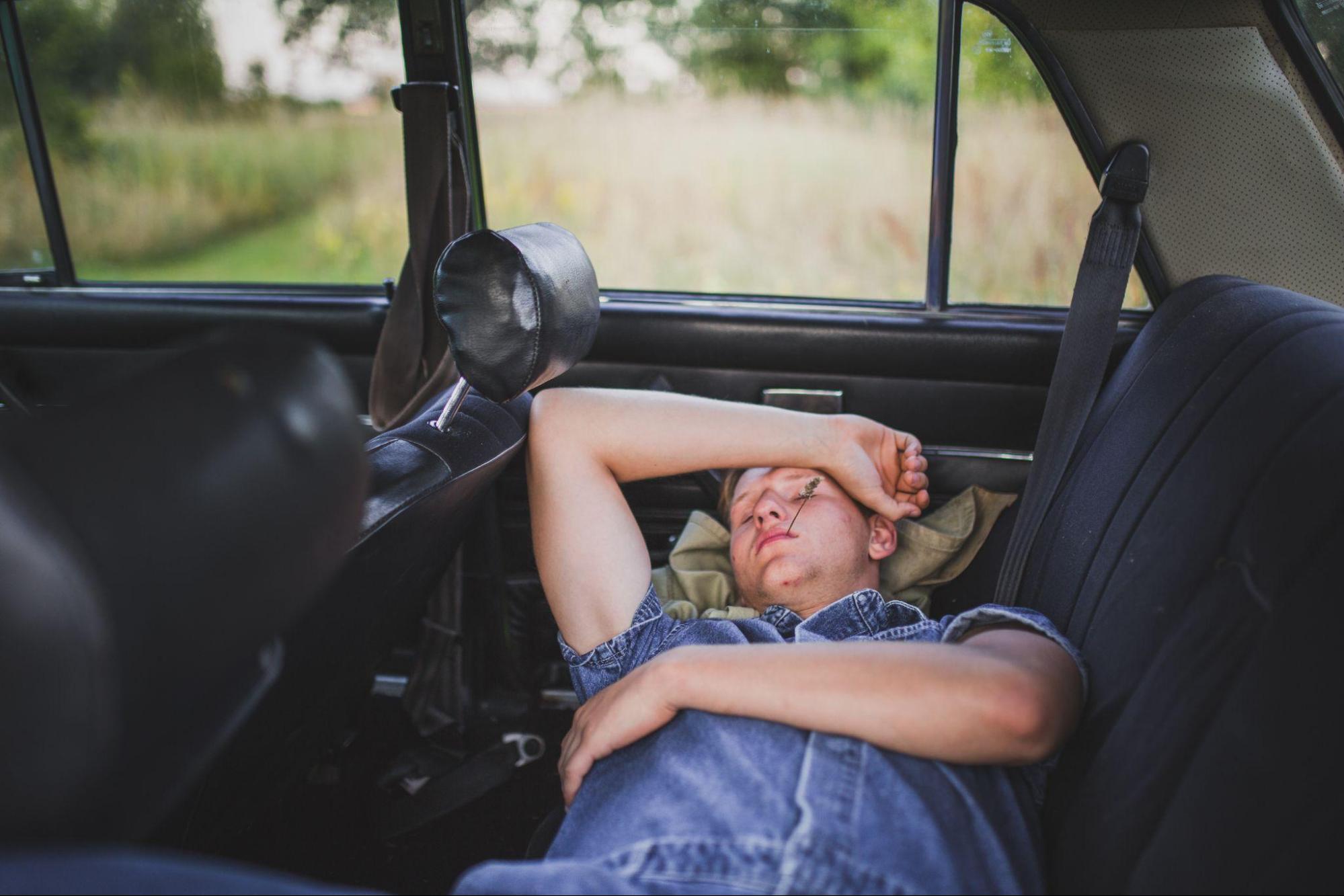 a tired man sleeping in the back of his car
