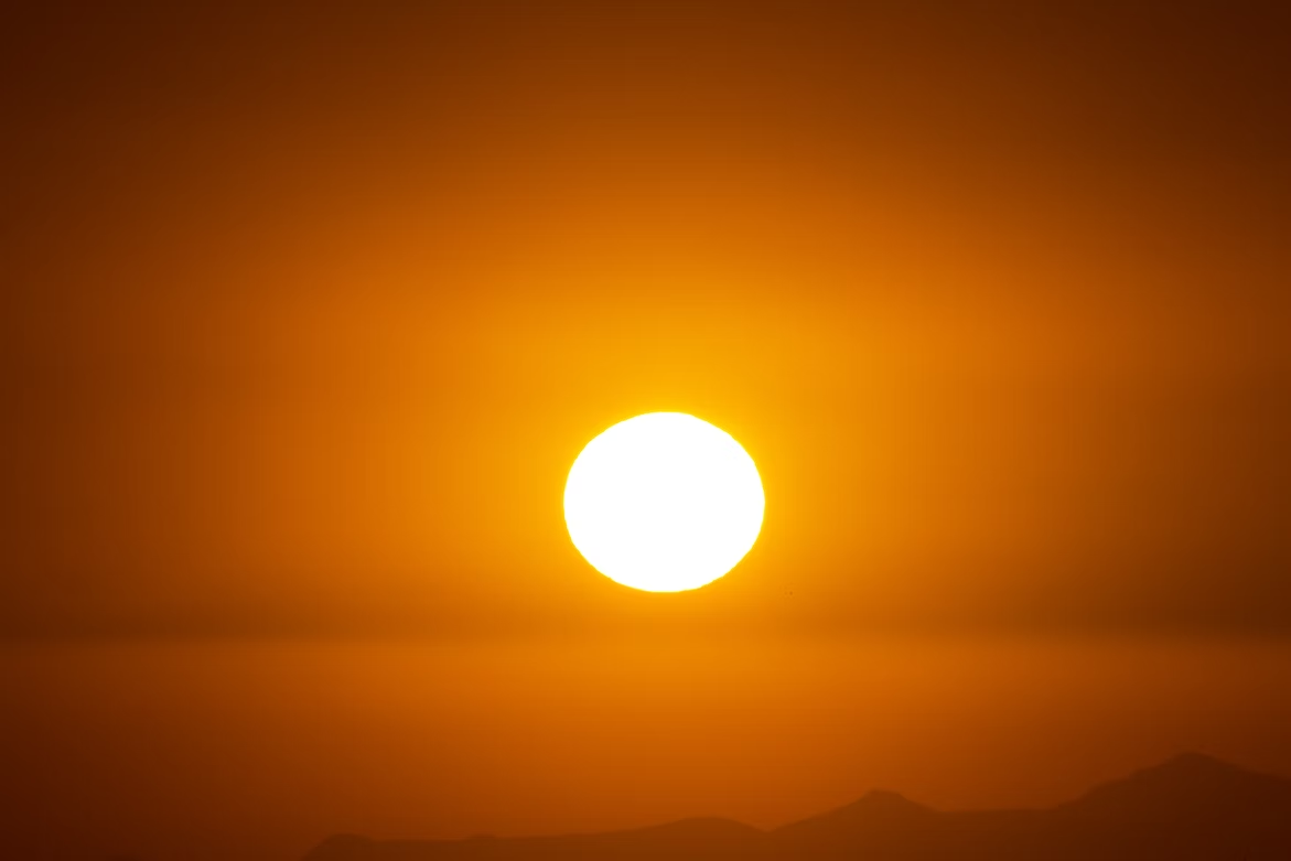 : a shot of the sun burning orange in the sky
