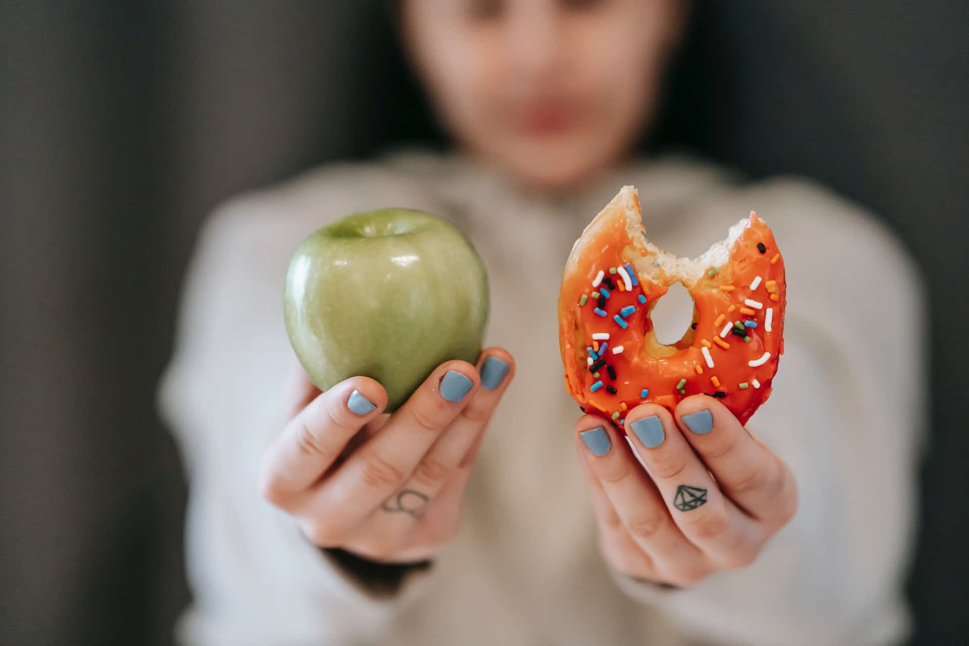 Out-of-focus woman holding an apple and donut