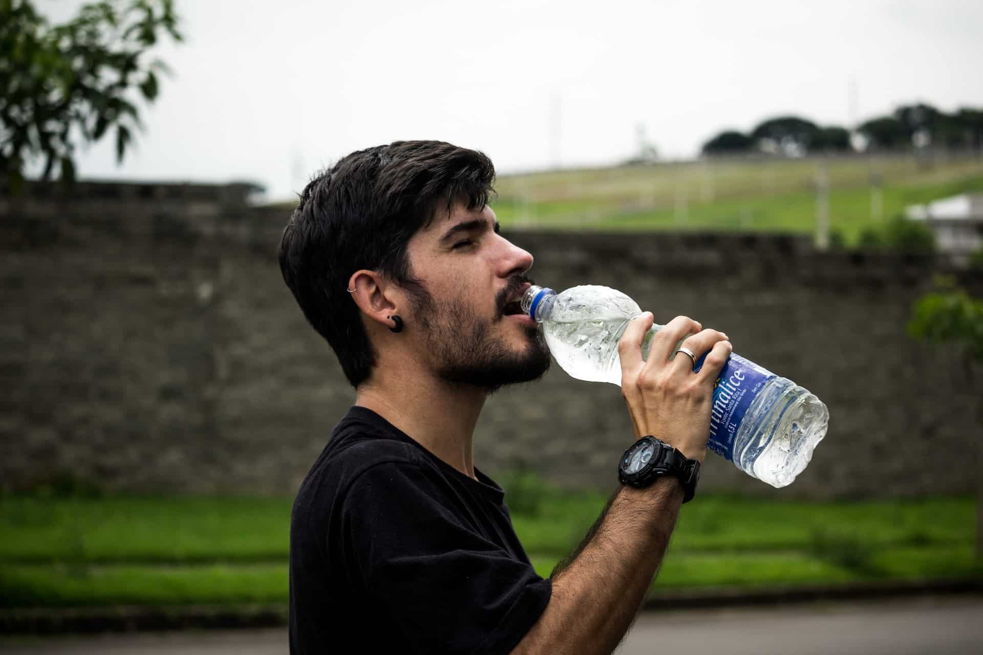 a man taking a drink from a large bottle of water