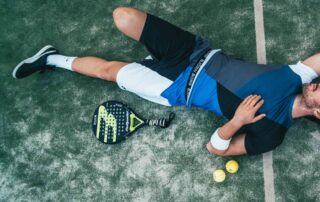 a man laying down next to a tennis racket