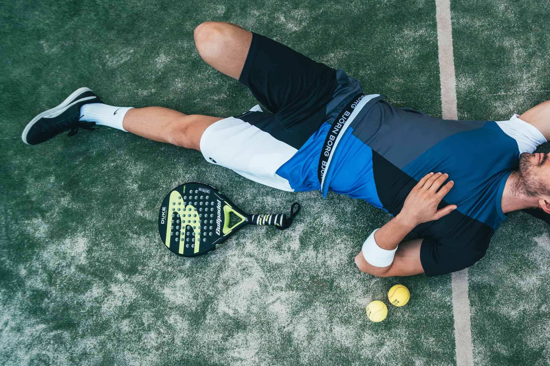 a man laying down next to a tennis racket