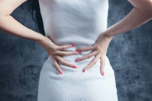 Person in a white dress holding her back