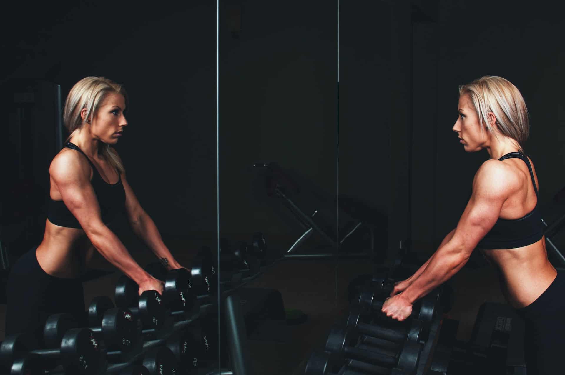 Woman lifting weights in front of a mirror