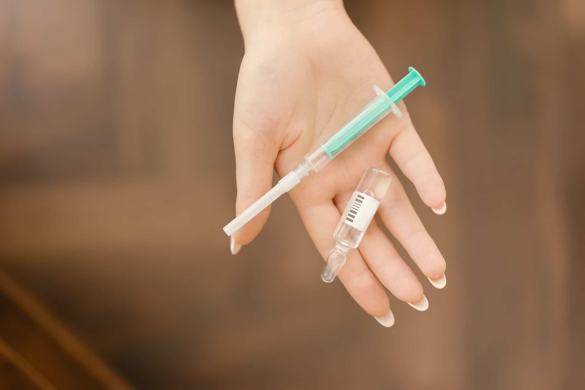 hand holding vial and syringe