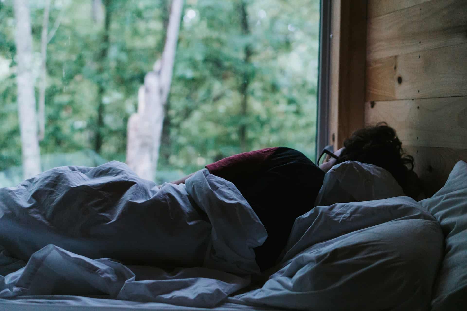 a person sleeping in bed next to a window