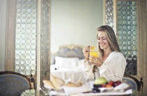A woman drinking orange juice and eating fruit in a fancy room