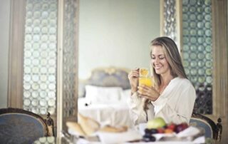 A woman drinking orange juice and eating fruit in a fancy room