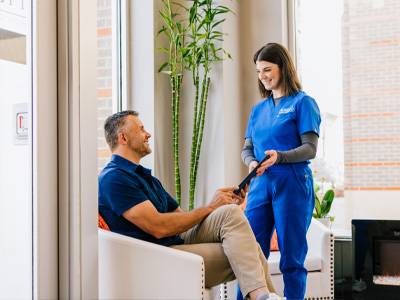 Staff talking to a man in a comfortable Prime IV lobby about filling out his health needs questionnaire