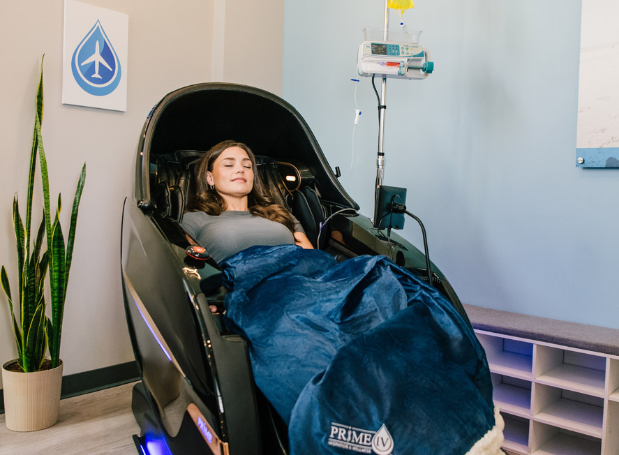 Woman relaxing in massage chair while getting an IV therapy drip