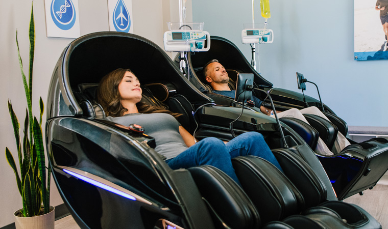 Man and woman get couples IV therapy treatment in massage chairs
