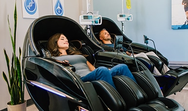 Man and woman get couples IV therapy treatment in massage chairs