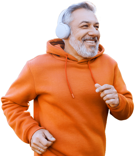 Smiling man in an orange hoodie wearing headphones while jogging